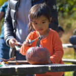 child painting pumpkin at family event